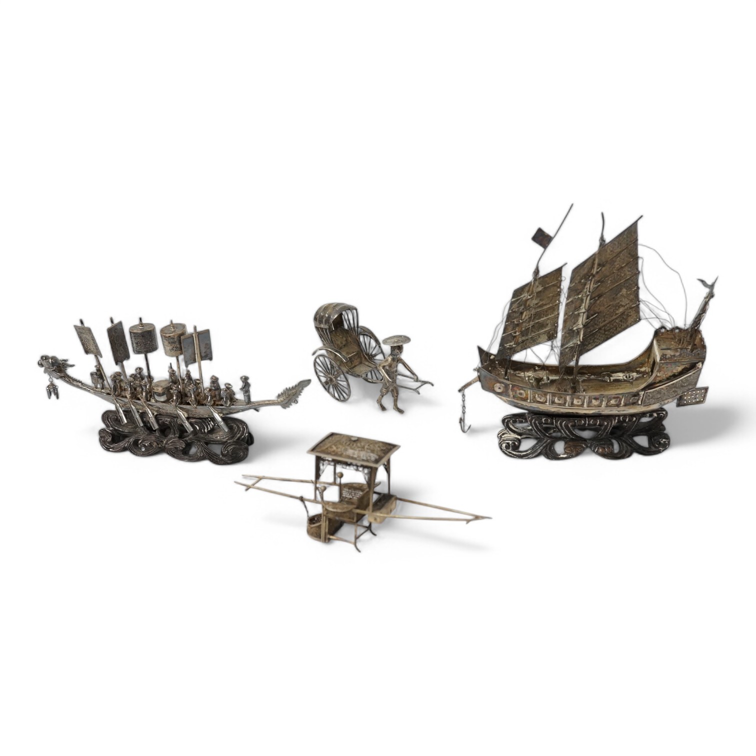 A Chinese white metal miniature model of a junk, length 11.2cm, on a wooden stand, a similar late 19th/early 20th century miniature filigree sedan chair and rickshaw by Kwan Wo and a Chinese white metal model of a boat w